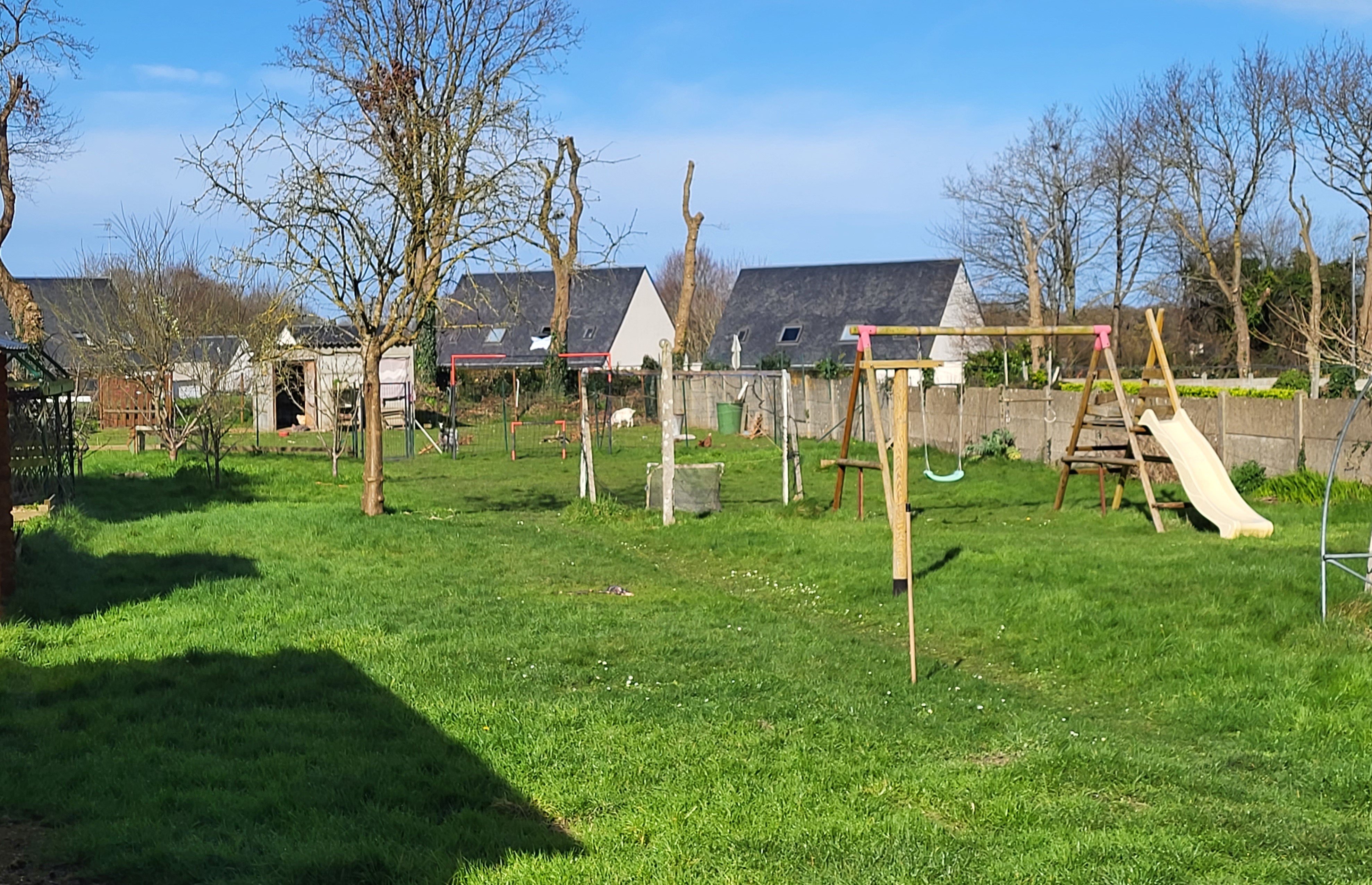 Grand jardin à l'arrière de la maison accueillant,  sur une partie, des poules et deux chèvres